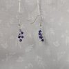 A pair of blue chainmail beaded earrings with six pearly blue glass seed beads per earring, connected by silver-colored jump rings and finished with sterling silver earring hooks.