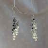 A pair of black-and-white gradient chainmail beaded earrings with 30 glass seed beads per earring, connected by silver-colored jump rings and finished with silver-colored earring hooks.