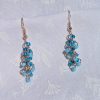 A pair of handmade earrings featuring three shades of blue glass seed beads, connected by rose-gold-colored jump rings and hooks in a cascading design.