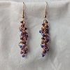 Dragon Scales Earrings featuring iridescent blue/purple, matte deep purple, and pearly amethyst beads, connected with rose-gold jump rings and matching hooks.