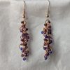 Dragon Scales Earrings featuring iridescent blue/purple, matte deep purple, and pearly amethyst beads, connected with rose-gold jump rings and matching hooks.
