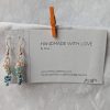 Ocean Tide earrings with 14 beads in seven ocean-inspired colors: clear, matte gray, pearly blue/gray, iridescent blue, metallic blue, matte deep blue, and solid indigo, connected with gold-colored jump rings and hooks.