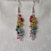 A pair of handmade dangle earrings featuring 24 transparent glass beads in rainbow colors, hanging from silver-colored jump rings and earring hooks.