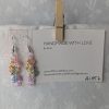 Handmade dangle earrings with 18 transparent pearly pastel beads in pink, orange, yellow, blue, periwinkle, and purple on silver-colored jump rings and earring hooks.