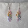 Handmade dangle earrings with 18 transparent pearly pastel beads in pink, orange, yellow, blue, periwinkle, and purple on silver-colored jump rings and earring hooks.