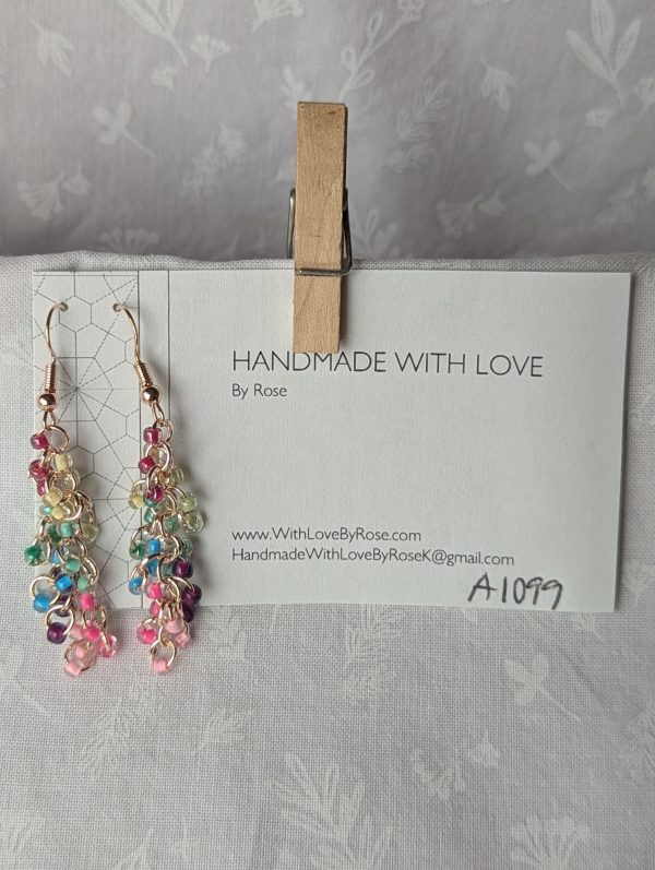 Radiance Lined Earrings: 27 clear glass beads, each lined in rainbow colors: red, yellow, seafoam, green, blue, purple, hot pink, and pale pink, connected with rose-gold-colored jump rings.