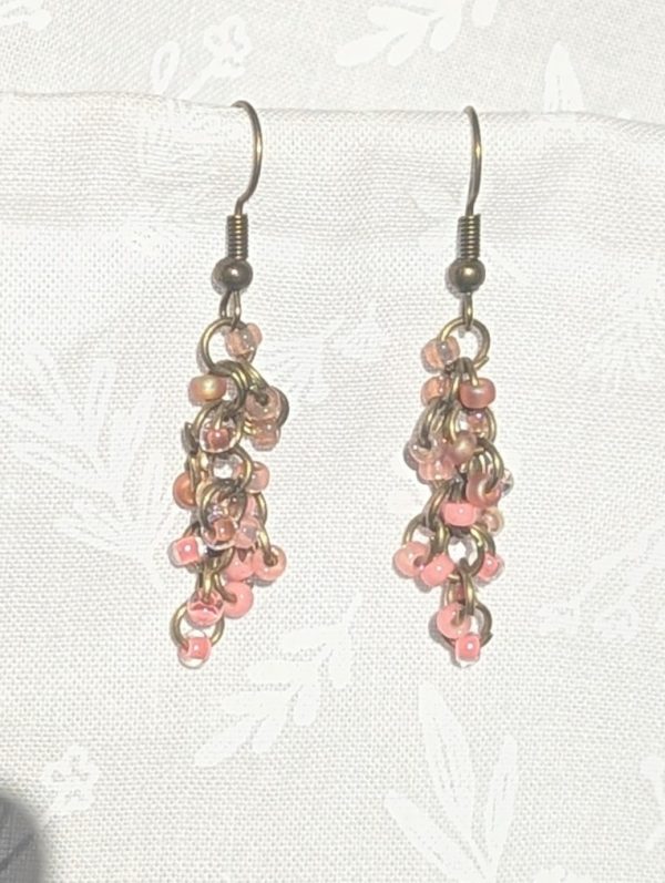 Caption: Blushed Bronze – Handmade dangle earrings featuring 18 beads in soft pink and mauve shades with bronze-colored jump rings and matching earring hooks.