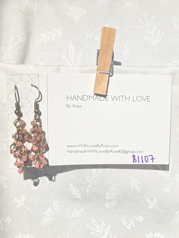 Caption: Blushed Bronze – Handmade dangle earrings featuring 18 beads in soft pink and mauve shades with bronze-colored jump rings and matching earring hooks.