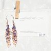 Moonlit Indigo: A pair of handmade earrings with 45 glass beads in shades of navy, dark blue, cream, and white, connected with rose-gold jump rings and hooks.