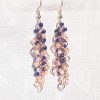 Moonlit Indigo: A pair of handmade earrings with 45 glass beads in shades of navy, dark blue, cream, and white, connected with rose-gold jump rings and hooks.