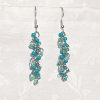 Forest Whispers — Handmade earrings with 27 green beads in shimmering, solid, and green-lined clear tones, connected with steel-colored jump rings and matching hooks.