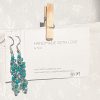 Forest Whispers — Handmade earrings with 27 green beads in shimmering, solid, and green-lined clear tones, connected with steel-colored jump rings and matching hooks.