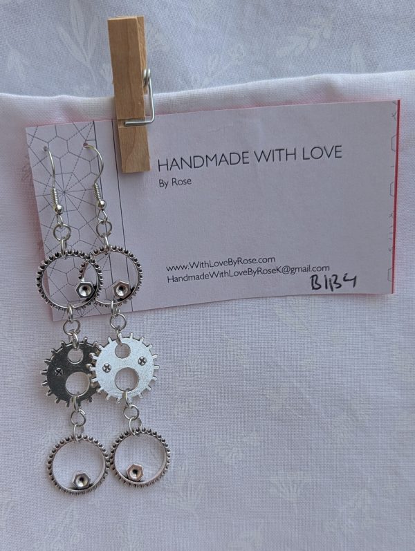 Industrial Elegance Earrings: Pair of silver-colored gear earrings with three interlinked gears, connected by silver jump rings and hung on silver earring hooks.