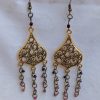 Gilded Ruby Cascade Earrings: Antiqued gold filigree earrings with five cascading bronze chains, each adorned with red-toned beads in multiple textures and finishes.