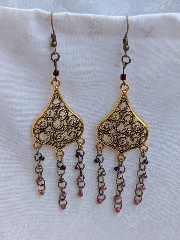 Gilded Ruby Cascade Earrings: Antiqued gold filigree earrings with five cascading bronze chains, each adorned with red-toned beads in multiple textures and finishes.