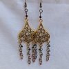 Gilded Ruby Cascade Earrings: Antiqued gold filigree earrings with five cascading bronze chains, each adorned with red-toned beads in multiple textures and finishes.