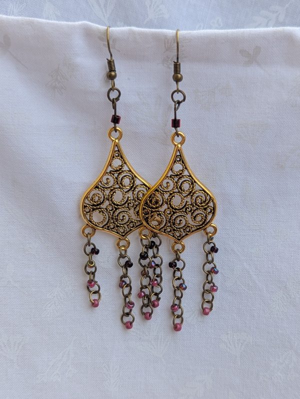 Gilded Ruby Cascade Earrings: Antiqued gold filigree earrings with five cascading bronze chains, each adorned with red-toned beads in multiple textures and finishes.