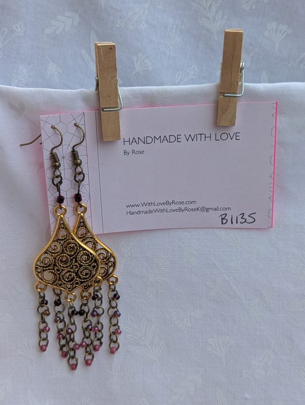 Gilded Ruby Cascade Earrings: Antiqued gold filigree earrings with five cascading bronze chains, each adorned with red-toned beads in multiple textures and finishes.