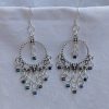Moonlight Mirage Earrings: Pair of silver-colored hoop earrings with dangling silver jump rings and blue iridescent cylindrical beads.