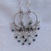 Moonlight Mirage Earrings: Pair of silver-colored hoop earrings with dangling silver jump rings and blue iridescent cylindrical beads.