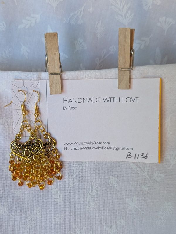 The Golden Hour Cascade Earrings: Pair of chandelier-style earrings with 25 glass beads in five shades and textures of gold, hung from antiqued gold ornaments with gold jump rings.