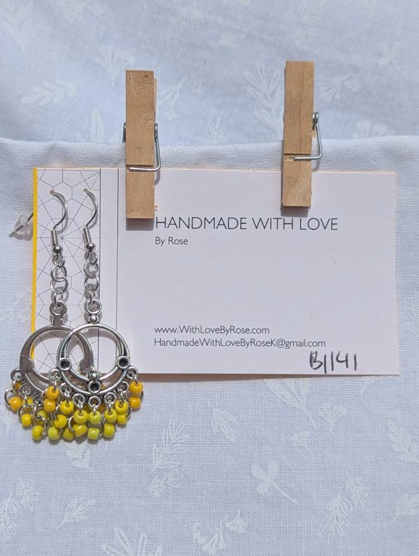 Sunspell Earrings: Silver circular filigree earrings with 14 dangling yellow beads in varied warm tones, including gold, marigold, and bright yellow, on steel-colored hooks.
