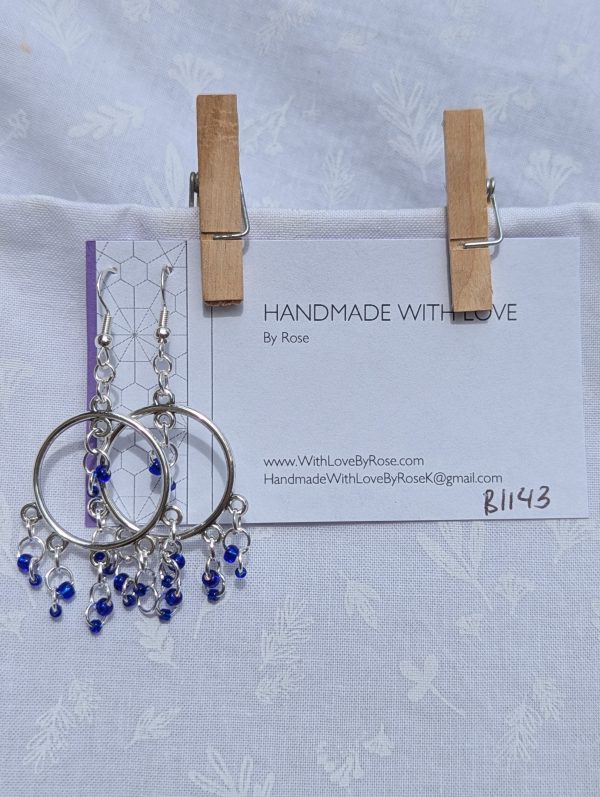 The Celestial Mobile Earrings: a pair of silver-colored hoop earrings with dangling silver jump rings and blue shiny glass beads