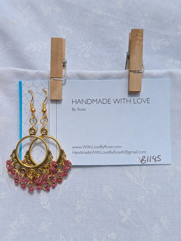 Rosé Reverie Earrings: Antique gold earrings with 18 rose-colored beads—featuring rose-lined clear and solid petal pink—hanging from ornate gold-toned ornaments.