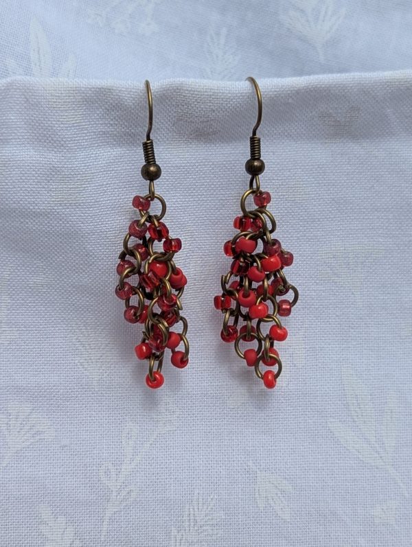 Molten Ruby Earrings—Earrings featuring 20 red glass beads in four textures—solid, matte, pearly, and silver-lined—connected with bronze-colored jump rings and hooks.