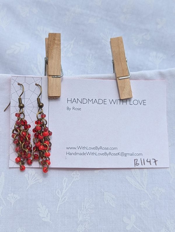 Molten Ruby Earrings—Earrings featuring 20 red glass beads in four textures—solid, matte, pearly, and silver-lined—connected with bronze-colored jump rings and hooks.