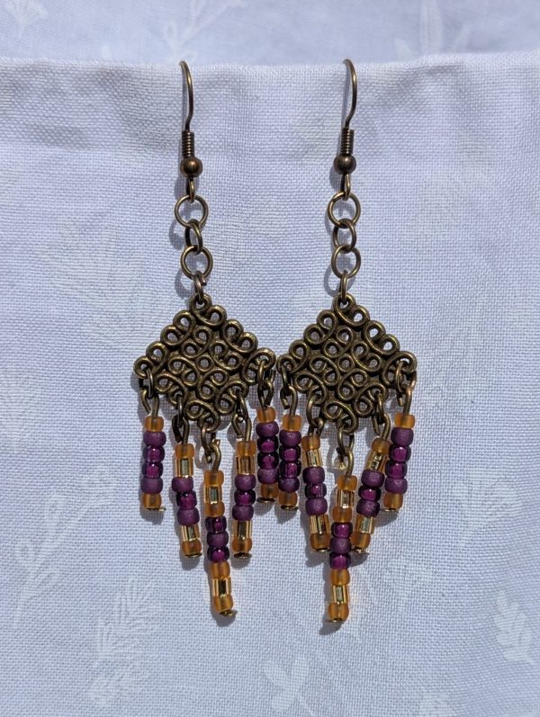 Saffron Twilight — Handmade bronze Tibetan-style earrings with 35 glass beads in plum, mulberry, gold-lined, and amber-gold tones.
