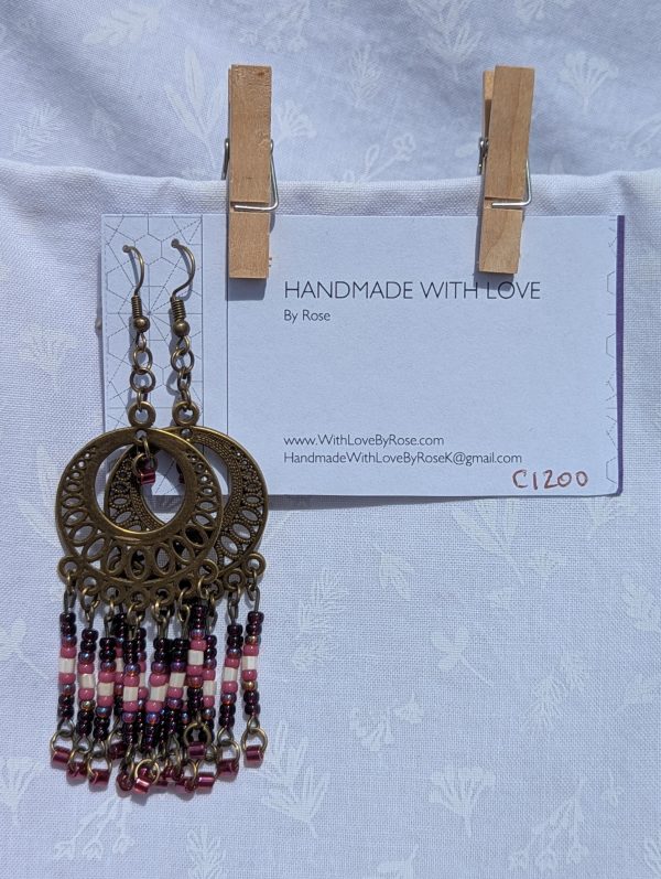 Desert Rose Sundial — Bronze filigree earrings with cascading glass beads in garnet, blush pink, ivory, rose, and crimson, arranged in five vertical strands.
