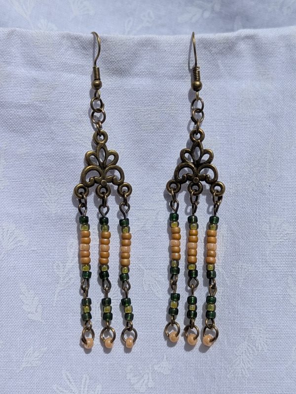 Verdant Bloom — Bronze chandelier earrings with floral Tibetan-style ornaments and dangling strands of amber, forest green, pale yellow, and ivory glass beads.