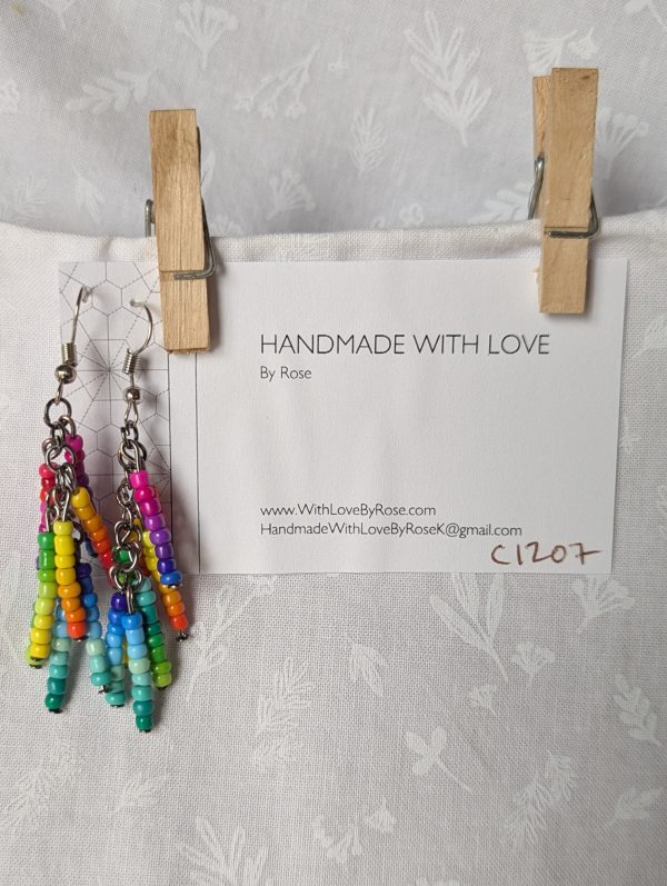Rainbow Burst Earrings: Vibrant handmade earrings featuring 64 glossy glass seed beads in 32 different rainbow colors, hung in 8 clustered strands from tungsten posts with steel hooks.