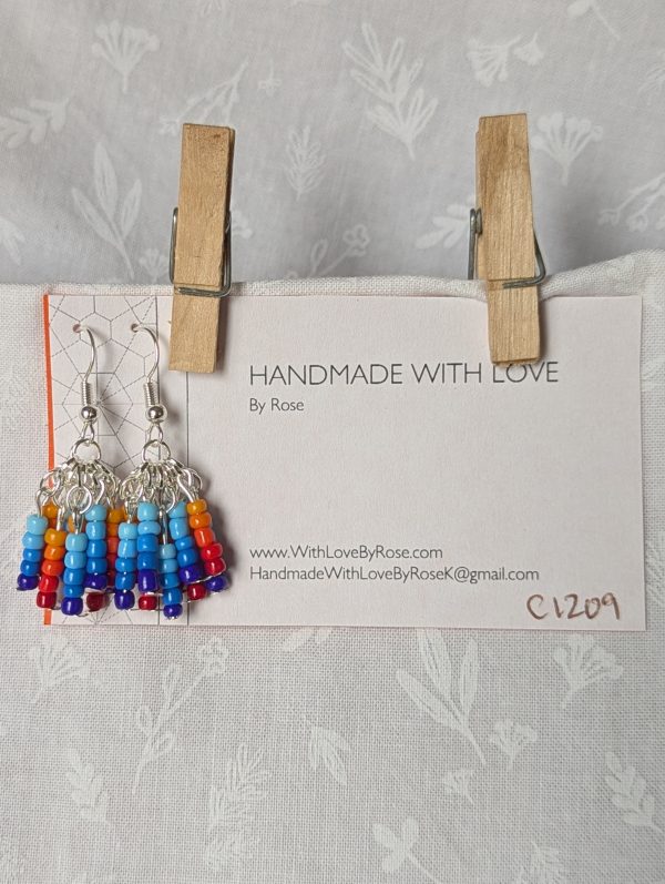 Fire and Ice Gradient Earrings – Gradient dangle earrings featuring 50 glass seed beads per earring in warm fire tones and cool ice hues, hung in strands from silver-colored posts with silver hooks.
