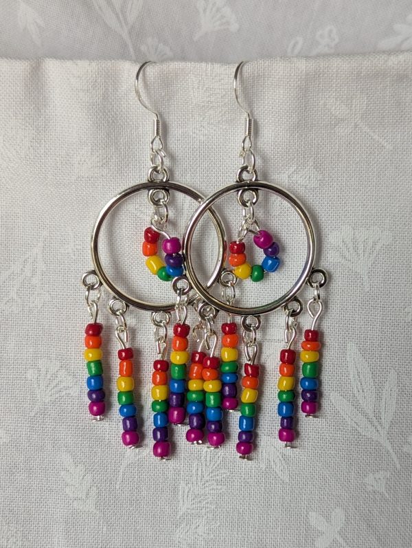 Rainbow circle earrings with silver hoops, five dangling rainbow strands, and a circular rainbow bead charm in the center.