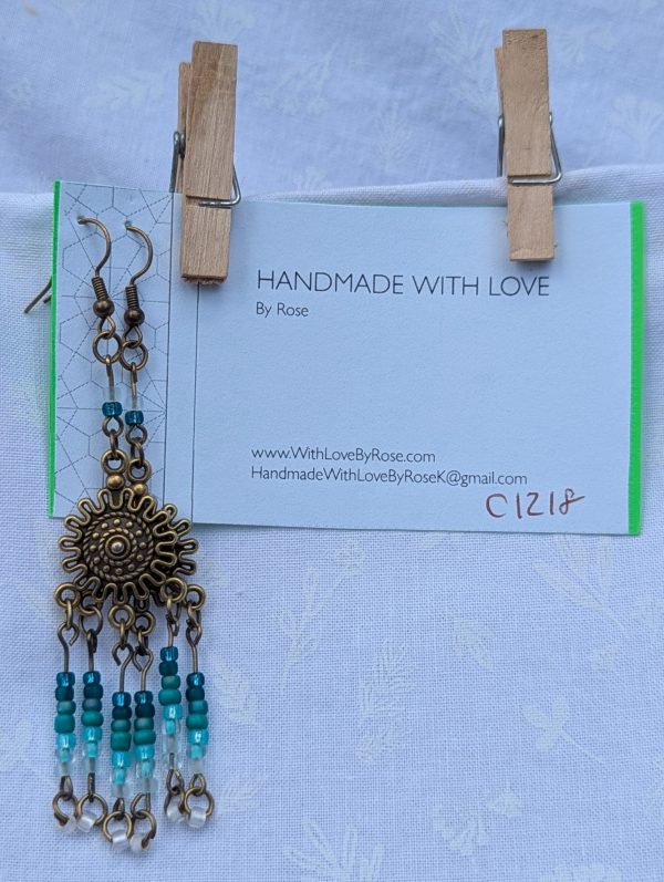 Sunburst Surf Earrings: Bronze sunburst earrings with hanging teal gradient beads in multiple shades.