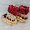 Handknit newborn baby booties in cream, red, and yellow with navy ties and a fiery red cuff, made from soft merino wool.