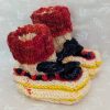 Handknit newborn baby booties in cream, red, and yellow with navy ties and a fiery red cuff, made from soft merino wool.