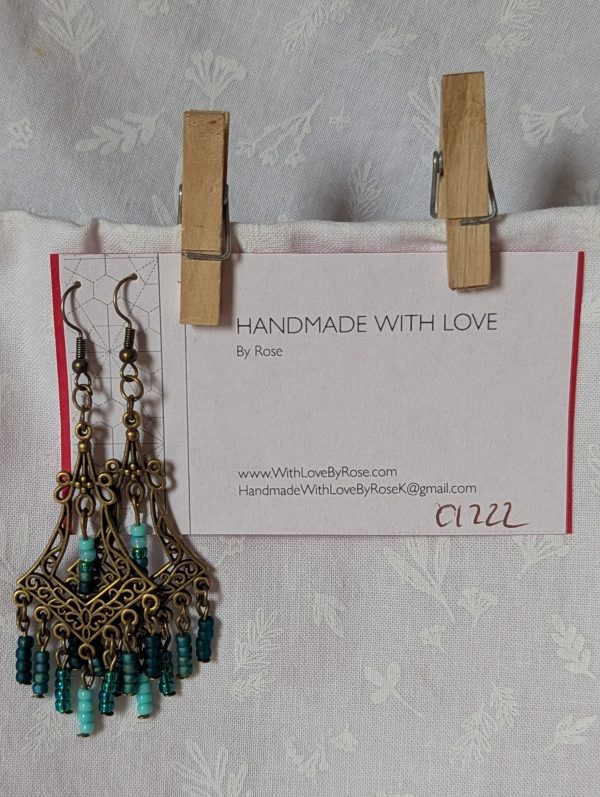 Teal Twilight Earrings with 29 teal glass beads in four ocean-inspired hues, hanging from ornate bronze filigree ornaments and bronze hooks.