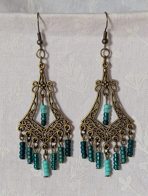 Teal Twilight Earrings with 29 teal glass beads in four ocean-inspired hues, hanging from ornate bronze filigree ornaments and bronze hooks.