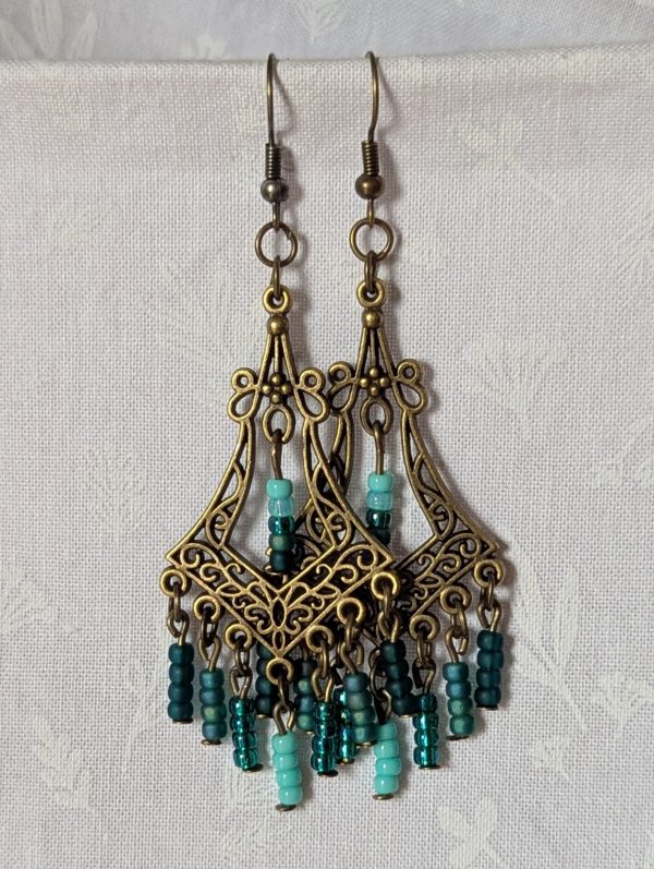 Teal Twilight Earrings with 29 teal glass beads in four ocean-inspired hues, hanging from ornate bronze filigree ornaments and bronze hooks.
