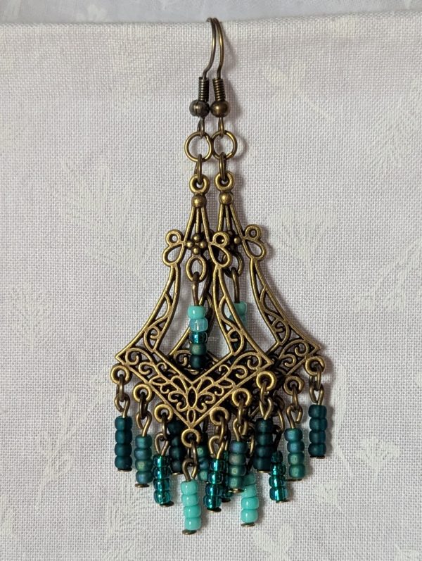 Teal Twilight Earrings with 29 teal glass beads in four ocean-inspired hues, hanging from ornate bronze filigree ornaments and bronze hooks.