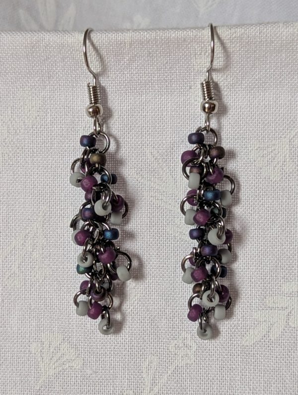 Shadow Galaxy Earrings with 27 beads in matte gray, frosted plum, and iridescent galaxy tones, linked with tungsten-colored rings and steel hooks.