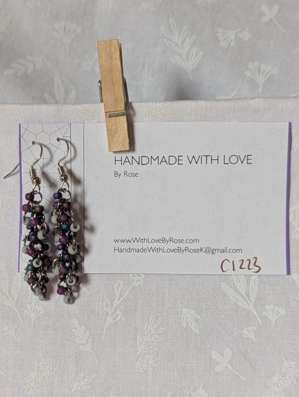 Shadow Galaxy Earrings with 27 beads in matte gray, frosted plum, and iridescent galaxy tones, linked with tungsten-colored rings and steel hooks.