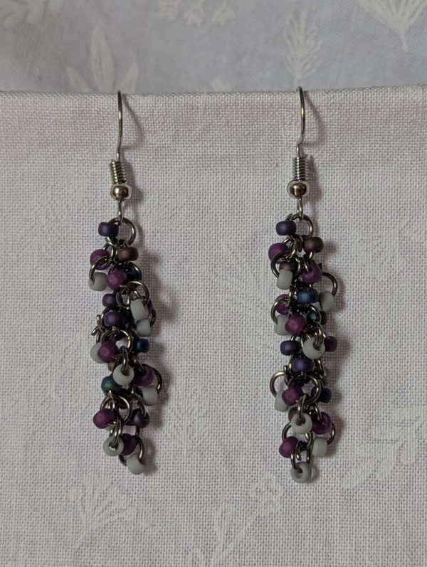 Shadow Galaxy Earrings with 27 beads in matte gray, frosted plum, and iridescent galaxy tones, linked with tungsten-colored rings and steel hooks.