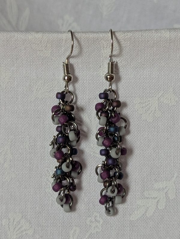Shadow Galaxy Earrings with 27 beads in matte gray, frosted plum, and iridescent galaxy tones, linked with tungsten-colored rings and steel hooks.