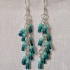 Ocean Whisper Earrings: A pair of handmade teal dangle earrings with 27 seafoam, silver-lined, and iridescent cyan beads. Suspended on silver jump rings with sterling silver hooks.