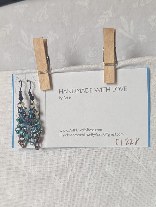 Starlight Drift Earrings: Handmade metallic galaxy earrings with 21 multicolored beads in seven cosmic shades, black hooks, and tungsten-toned jump rings.