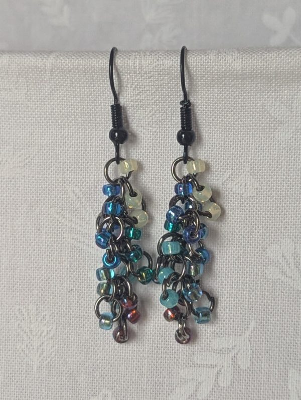 Starlight Drift Earrings: Handmade metallic galaxy earrings with 21 multicolored beads in seven cosmic shades, black hooks, and tungsten-toned jump rings.